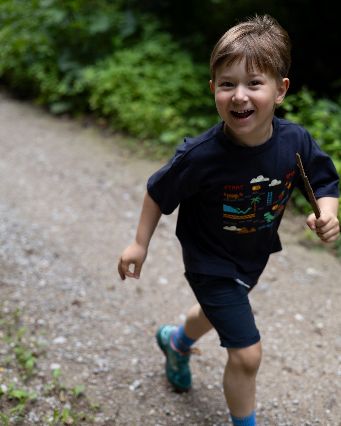 Der Bub l&auml;uft lachend den Waldweg entlang