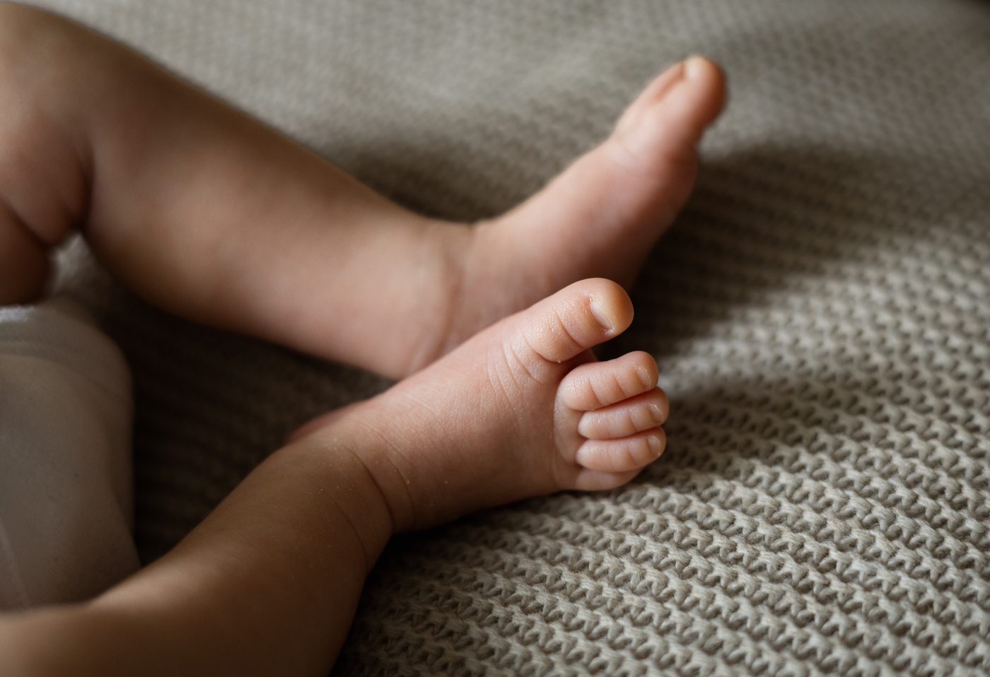 Zwei winzige Babyf&uuml;&szlig;e auf einer Strickdecke