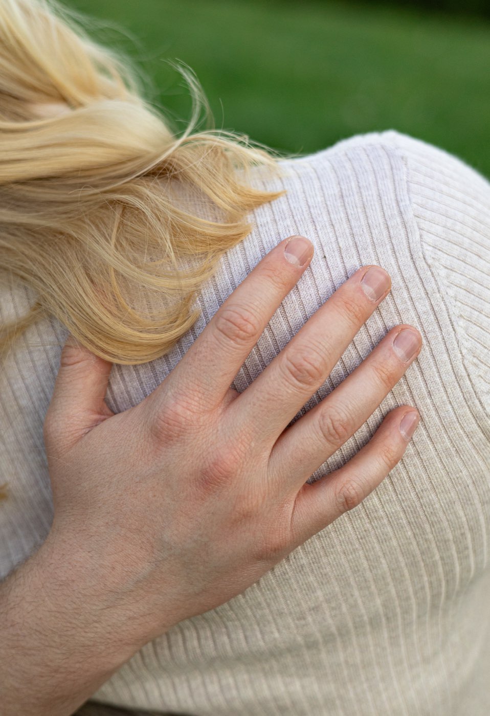 Nahaufnahme einer Hand auf der Schulter der Partnerin während einer Umarmung
